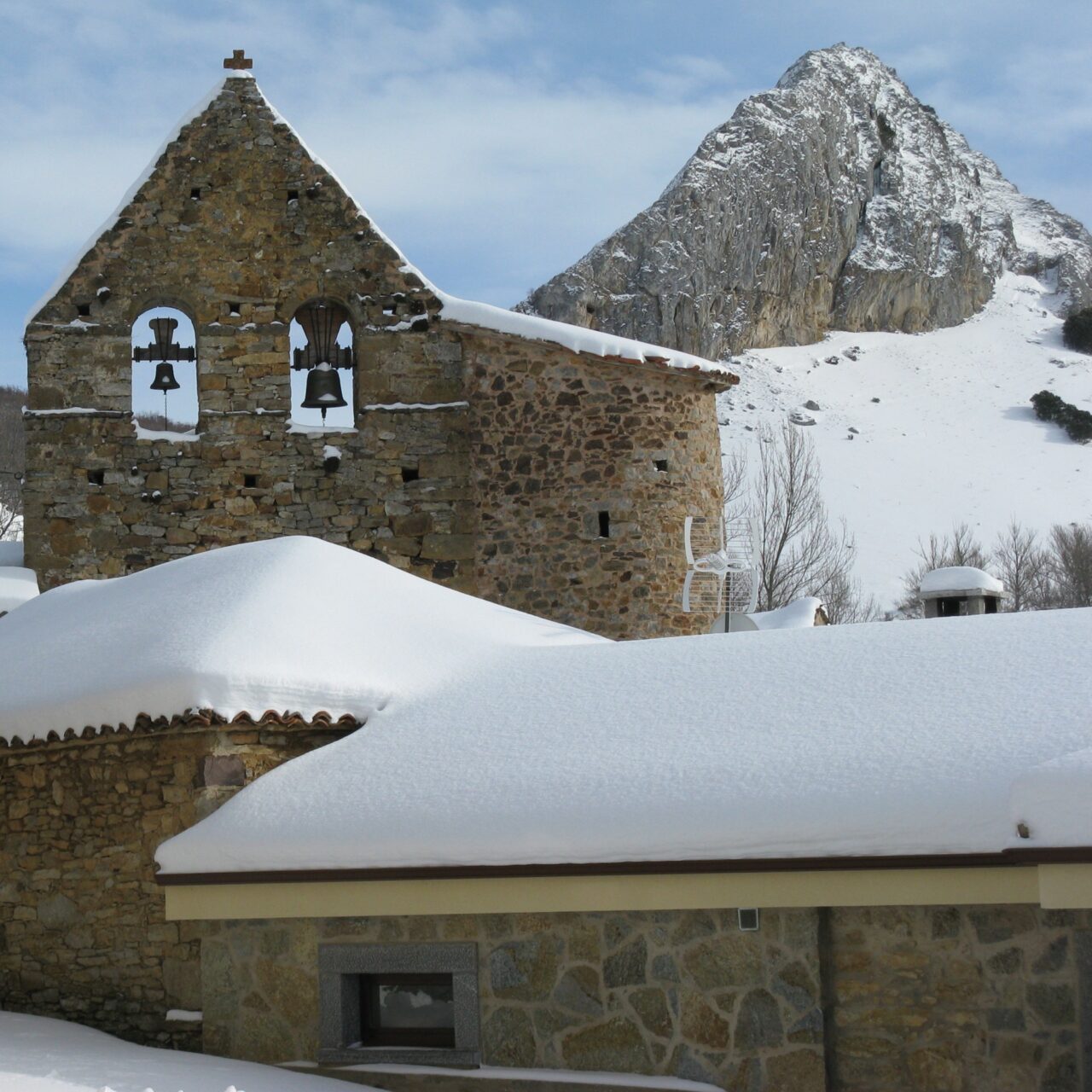 Espadaña de la iglesia y la Peña El Palo al fondo